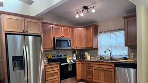 A kitchen with wooden cabinets, stainless steel appliances, a microwave, and a dishwasher. - The Sunset Perch | Pet-Friendly + Deck (Eureka Springs)