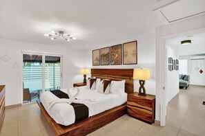 A bedroom with a wooden bed, two bedside tables with lamps, a ceiling fan, and artwork on the wall.