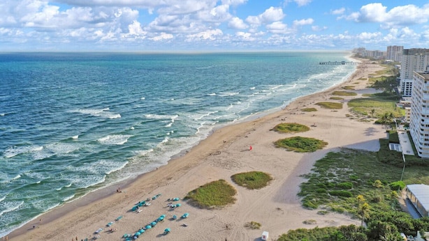 A beach with a view of the ocean, a pier, and a hotel with multiple floors. - Modern 1BR Beachside | Heated Pool + Parking (Pompano Beach)