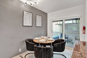 A dining area with a round table, black chairs, and two framed menus on the wall. - Coastal 1BR | Heated Pool | Steps to Beach (Pompano Beach)