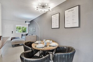 A modern dining area with a round table, black leather chairs, and a menu on the wall.