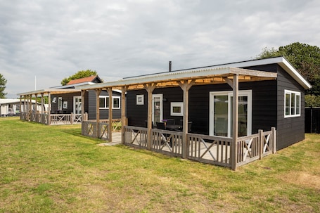 A row of cabins with wooden decks and large windows.. Holstebro Søpark