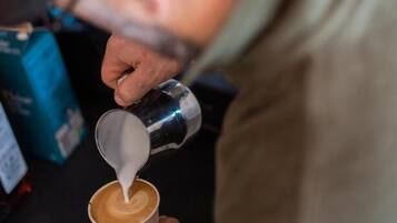 Una persona vertiendo leche en una taza de café.