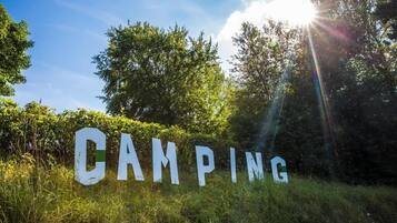 A sign with the word 'CAMPING' in large letters, surrounded by greenery.