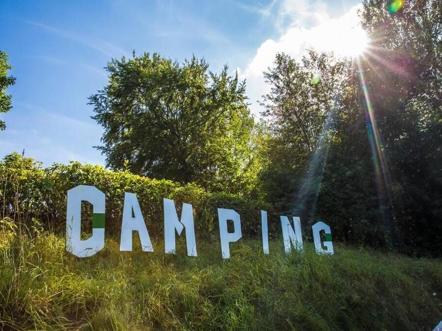A sign with the word 'CAMPING' in large letters, surrounded by greenery.