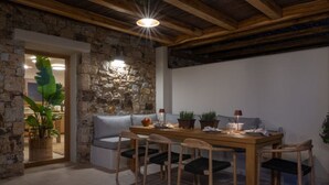 A dining area with a stone wall, wooden ceiling, and a table with chairs. - Casa di Nikolas Plaka Naxos (Plaka)