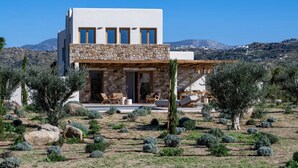 A modern house with a stone facade, a balcony with seating, and a view of the surrounding landscape. - Casa di Nikolas Plaka Naxos (Plaka)