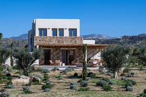 Ein modernes Haus mit einer Stein-Fassade, einem Balkon mit Sitzgelegenheit und Blick auf die umliegende Landschaft.