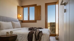 A bedroom with a bed, bedside table, and a window with a view. - Casa di Nikolas Plaka Naxos (Plaka)