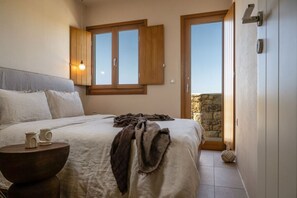 Ein Schlafzimmer mit Bett, Nachttisch und Fenster mit Blick.