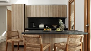 A modern kitchen with a central island, two wicker chairs, and a variety of kitchen appliances. - VILLA KERAMEAS PLAKA NAXOS (Plaka)