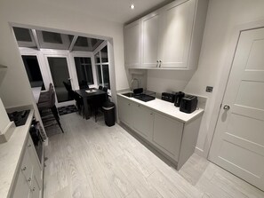 A compact kitchen with a dining area, a built-in stove, and a small sink. - Luxury 4 Bedroom House in Harrow (London)