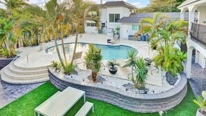 A swimming pool surrounded by palm trees and a white building.