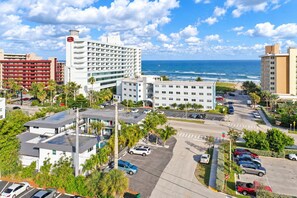 A coastal hotel with multiple buildings, parking areas, and a view of the ocean.