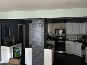 Una cocina moderna con armarios blancos, estufa de acero inoxidable y salpicadero de azulejos.