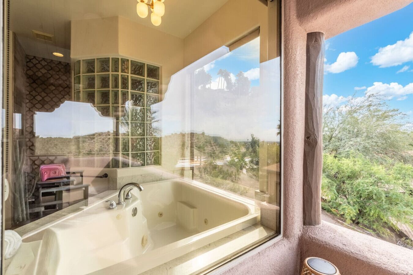 A bathroom with a large bathtub, a window with a view of a landscape, and a towel rack.