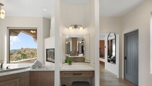 A modern bathroom with a large window, a built-in fireplace, a vanity with a mirror, and a bench. - NEW | HTD Pool | Firepit | Biltmore | Piestewa (Phoenix)