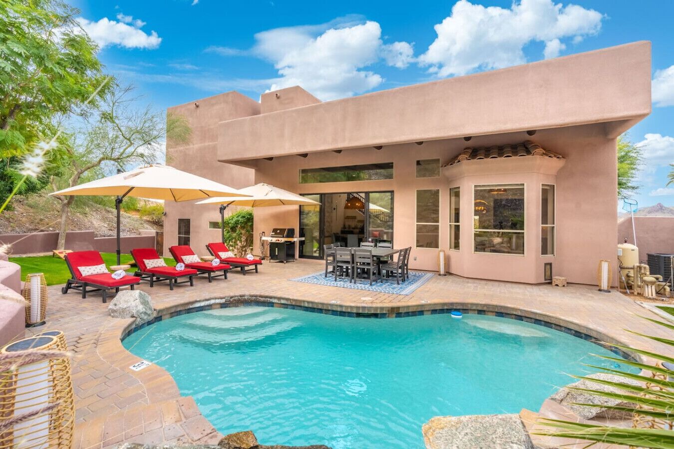 Una casa moderna con piscina, mobiliario de exterior y una zona de patio.