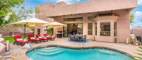 Una casa moderna con piscina, mobiliario de exterior y una zona de patio.