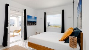 Ein Schlafzimmer mit einem Bett, Blick ins Freie und einer Tür, die auf einen Balkon führt.