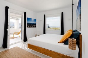 Une chambre avec un lit, une vue sur l’extérieur et une porte donnant sur un balcon.