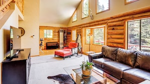 A log cabin interior with a leather sofa, a red armchair, a glass coffee table, and a television on a black stand. - Rebels Retreat-Minutes from Main St, Longtime Guest Favorite now with IronStone! (Ouray)