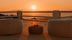 A sunset view from a balcony with two bean bags and a small table with drinks. - BLUE EYES VILLA Naxos Cyclades Greece (Naxos)