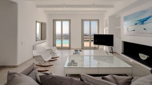 A spacious living area with a large TV, a glass coffee table, and a sofa. - BLUE EYES VILLA Naxos Cyclades Greece (Naxos)
