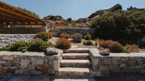 A stone staircase leading up to a building with a wooden roof, surrounded by shrubs and rocks. - BLUE EYES VILLA Naxos Cyclades Greece (Naxos)