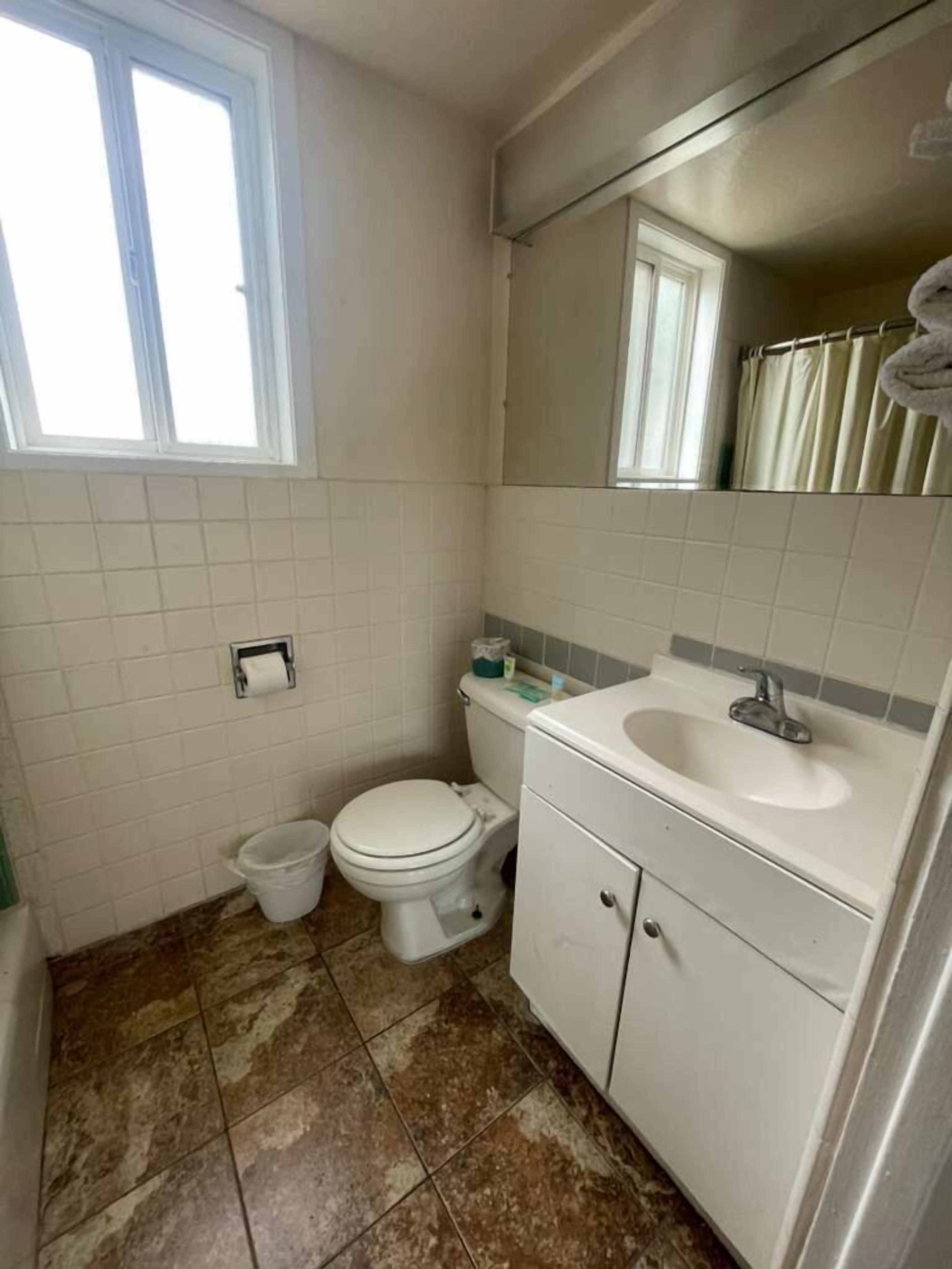 A small bathroom with a toilet, sink, and mirror.