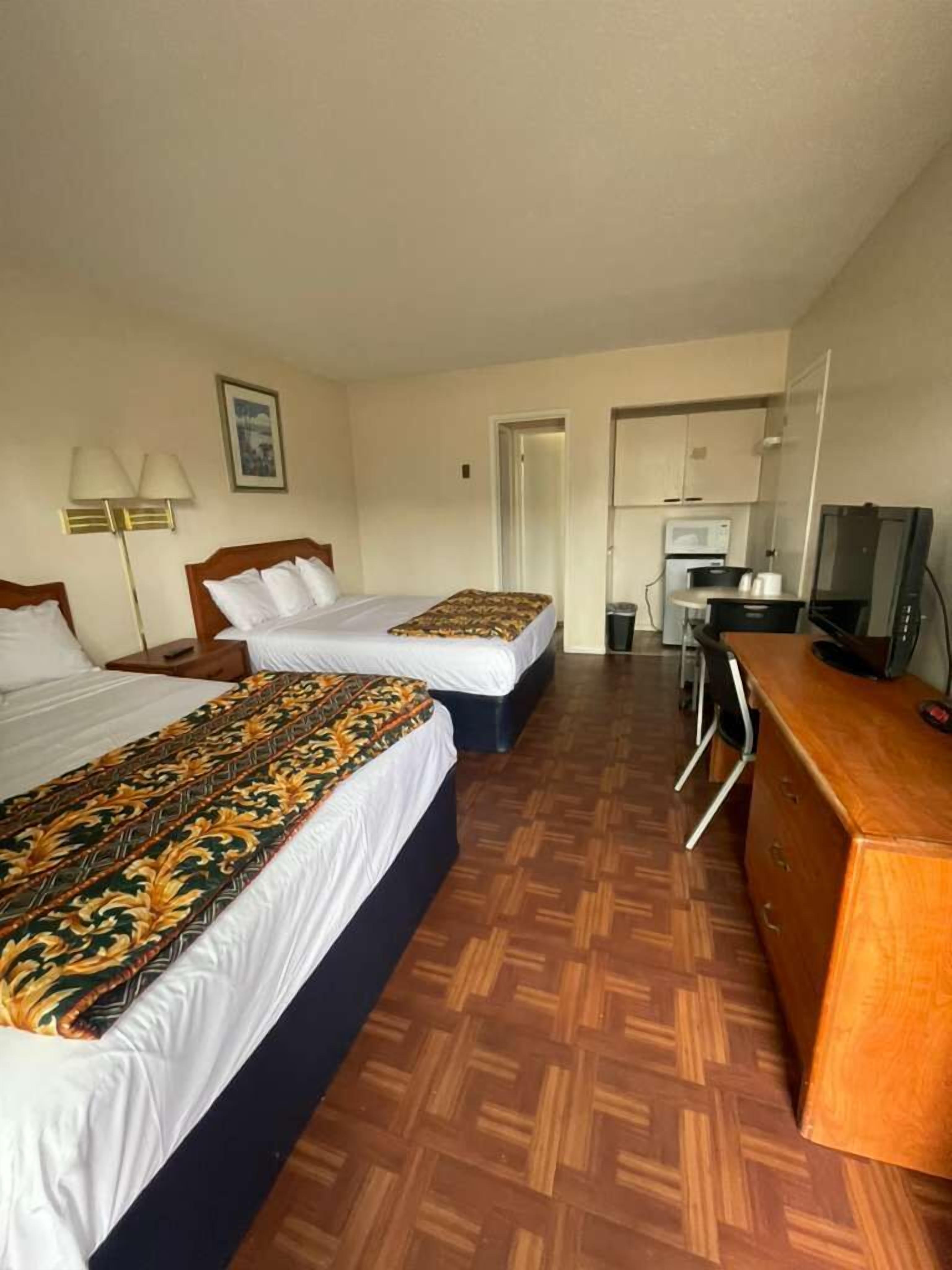 Une chambre d’hôtel avec deux lits, un bureau, une télévision et une kitchenette.
