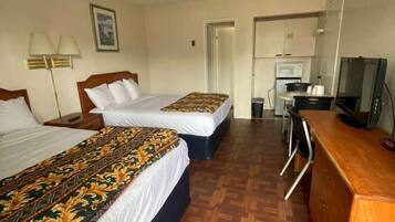 Une chambre d’hôtel avec deux lits, un bureau, une télévision et une kitchenette.