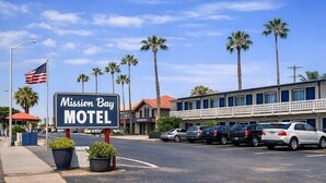 Señal de motel, coches aparcados y palmeras.