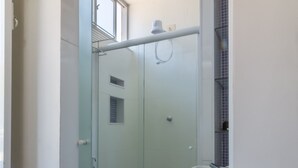 A bathroom with a glass-enclosed shower, a white sink, and a toilet. - Moderno Studio en Rio de Janeiro T915 (Rio de Janeiro)