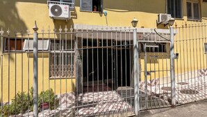 A yellow building with a gated entrance, air conditioning units, and a tiled patio area. - Moderno Studio en Rio de Janeiro T915 (Rio de Janeiro)