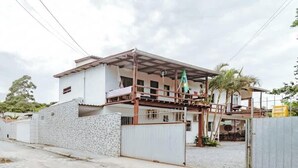 Una casa de dos pisos con balcón, patio cercado y cielo despejado.