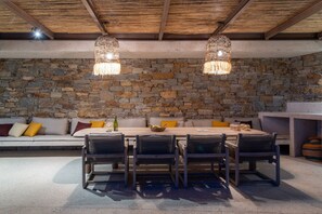 Ein Zimmer mit Steinwänden, Holzboden und einer Bank aus Stein sowie einem Tisch mit Stühlen.