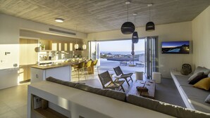 Un intérieur moderne comprenant une cuisine, un coin repas et un salon avec vue sur la mer.