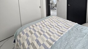 Ein Schlafzimmer mit Bett, Kleiderschrank, Tür und Spiegel.