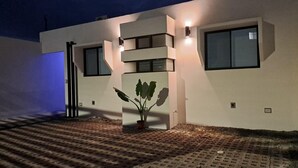 Ein modernes Gebäude mit flachem Dach, großen Fenstern und einem Blumentopf im Eingangsbereich.
