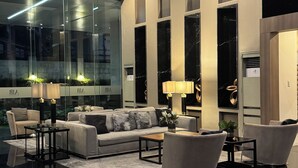 Ein modernes Wohnzimmer mit einer Couch, Sesseln, einem Couchtisch und einer Glaswand.