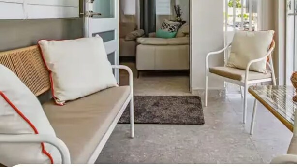 Una habitación con sofá, una silla, una mesita y vistas al exterior.