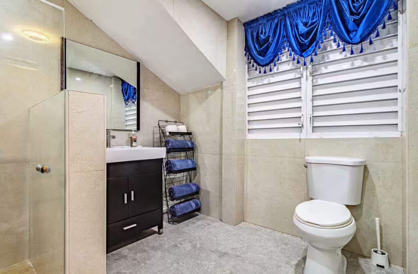 Un baño con inodoro, lavamanos, espejo, toallero y zona de ducha.