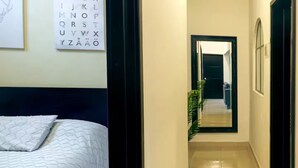 A hotel room with a bed, a wall-mounted alphabet chart, and a hallway leading to another room. - Nahualli Hospedaje Boutique /5 recámaras céntrico (Zacatlán)