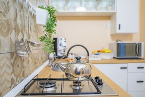 Una cocina con estufa a gas, hervidor y microondas.