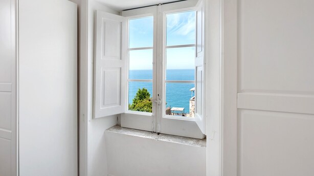 Eine weiße Tür mit Fenster, durch das Meer zu sehen ist.