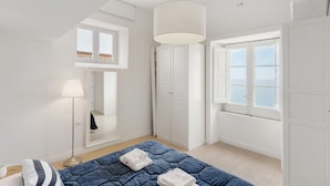 Ein Schlafzimmer mit Bett, Lampe, Schrank und Fenster mit Blick.
