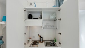 Cocina compacta con pileta, estufa y estanterías abiertas.