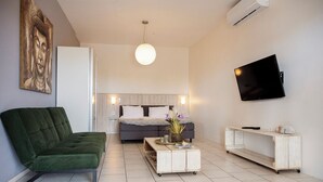 A modern living room with a green sofa, a coffee table, a TV, and a bed with a headboard. - Studio Bientu- centrally located-near trendy beaches (Sint Michiel)