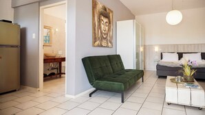 A modern living room with a green sofa, a white coffee table, and a Buddha painting on the wall. - Studio Bientu- centrally located-near trendy beaches (Sint Michiel)